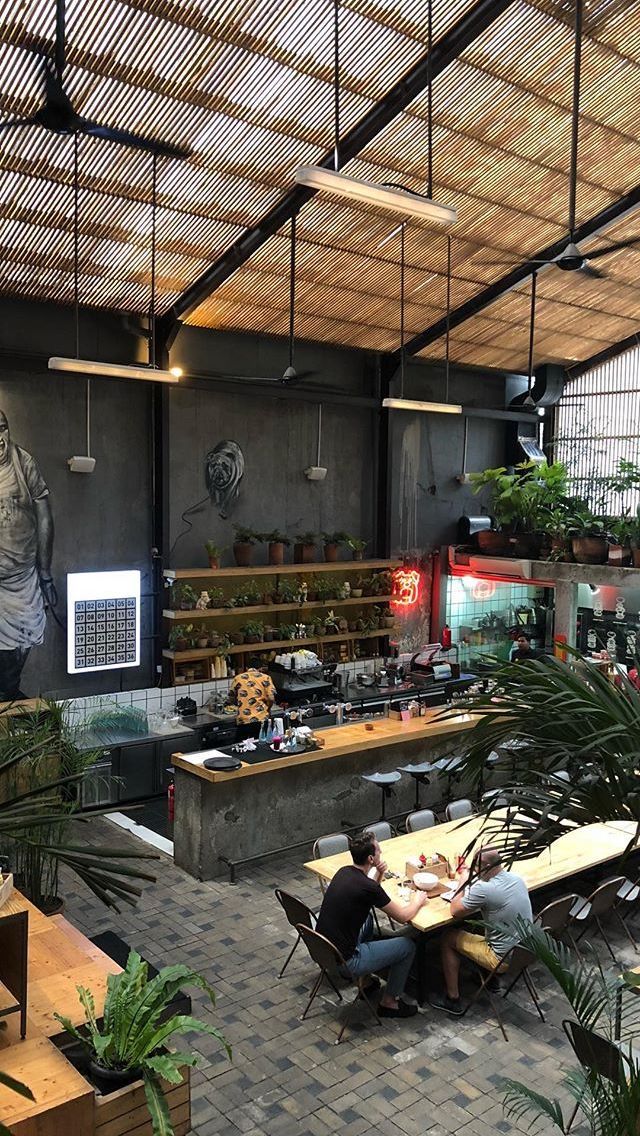 two people sitting at a table in a large room with lots of potted plants