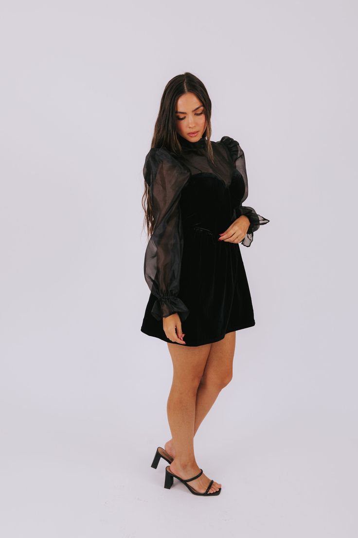 This playful mini dress features a cut out in the back for added allure, while the bodice's boning provides a flattering fit. Tied with a bow in the back of the neck, this spell on you dress is perfect for a night out. With long sheer sleeves and elastic cuffs, it adds the perfect touch of edginess to your wardrobe. Details Black mini dress Cut out in back Boning in bodice Tied bow in back of neck Long sheer sleeves Elastic in cuffs Velvet bodice Invisible zipper Fully lined Wired and padded cup Flirty Cocktail Dress With Sheer Sleeves, Backless Mini Dress With Tie Back For Party, Glamorous Cocktail Mini Dress With Tie Back, Party Backless Mini Dress With Tie Back, Party Puff Sleeve Dress With Tie Back, Flirty Mini Dress With Sheer Sleeves For Party, Glamorous Mini Dress With Sheer Sleeves For Night Out, Flirty Mini Dress With Sheer Sleeves For Evening, Backless Dress With Bow Tie Back For Night Out