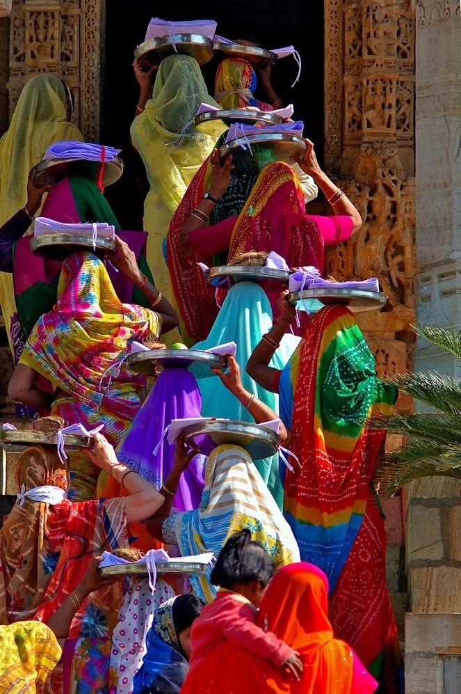 women in colorful sari carrying baskets on their heads