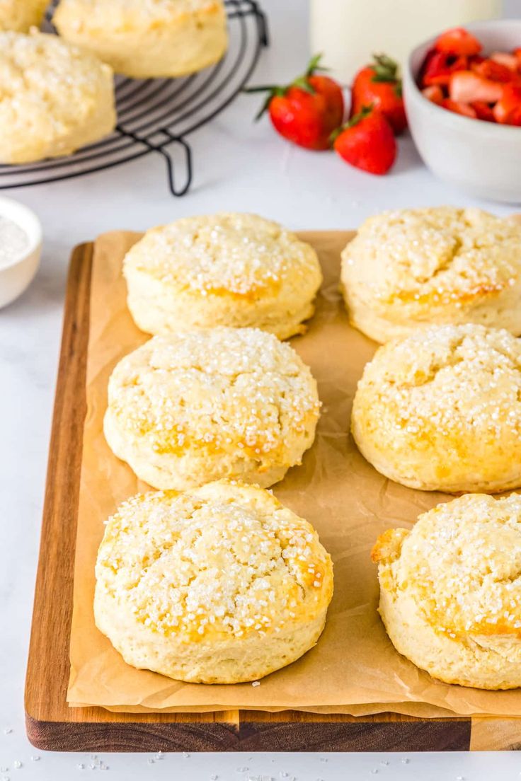 freshly baked biscuits on a cutting board with strawberries in the background