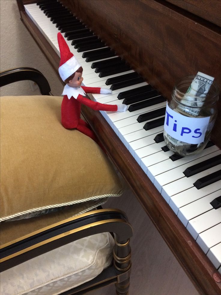 an elf sitting on top of a piano next to a jar of money