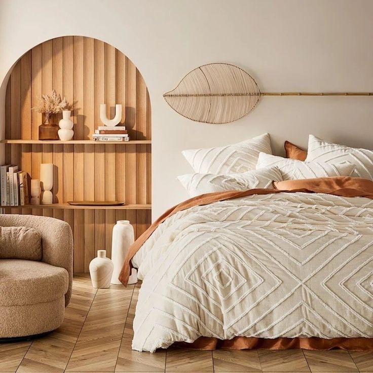 a large bed sitting next to a chair and book shelf on top of a wooden floor