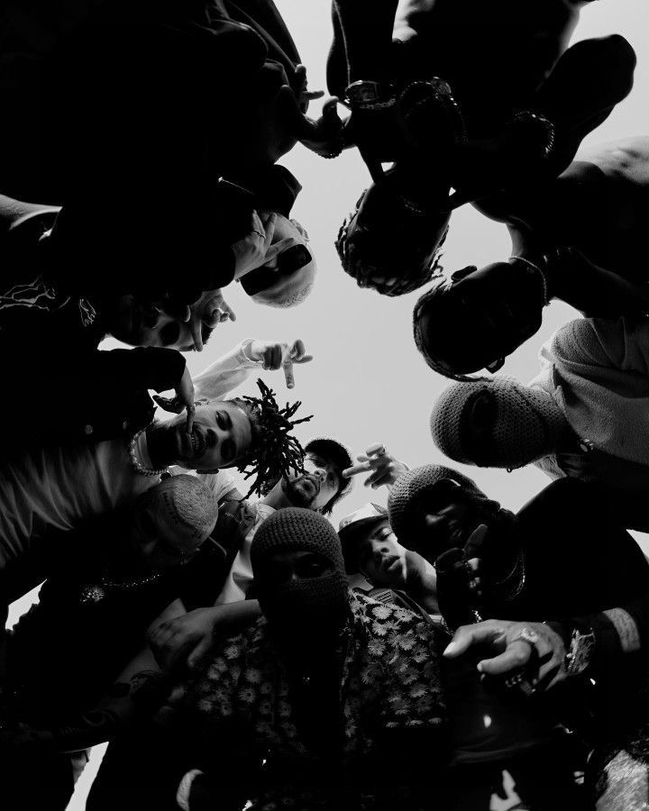 a group of people standing in a circle looking up at the sky with their hands together