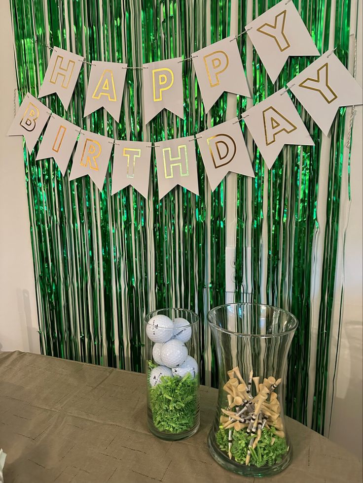 a happy birthday banner is hanging over a table with rocks and grass in front of it