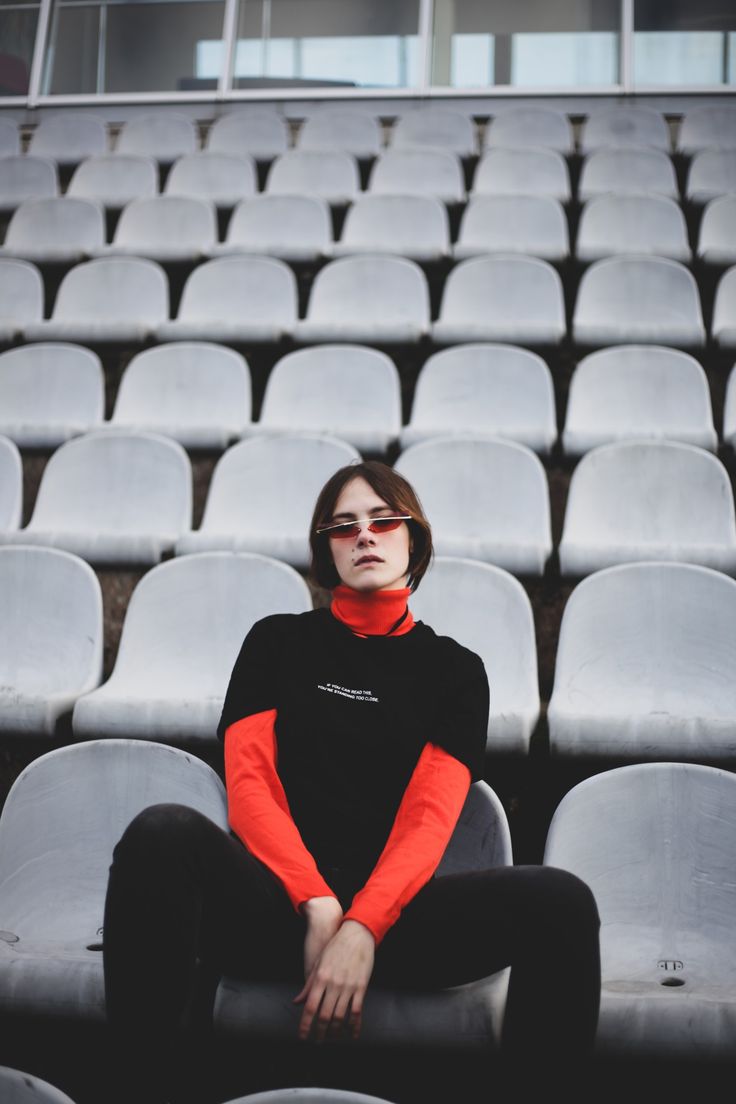 a woman in black and red sitting on the bleachers