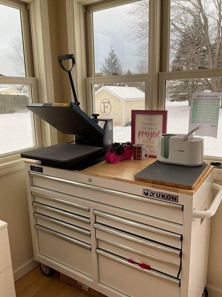 a workbench with many drawers and tools on it in front of two windows