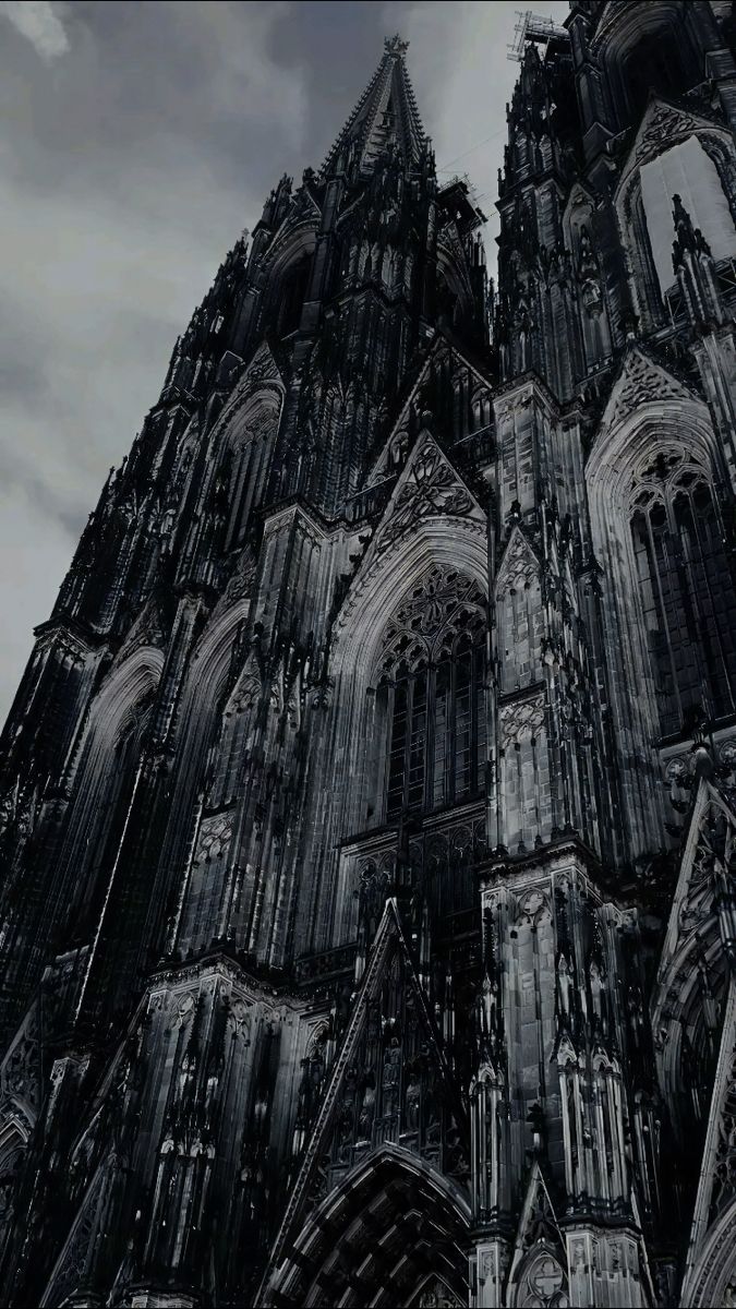 the large cathedral has many spires on it's sides and is surrounded by dark clouds