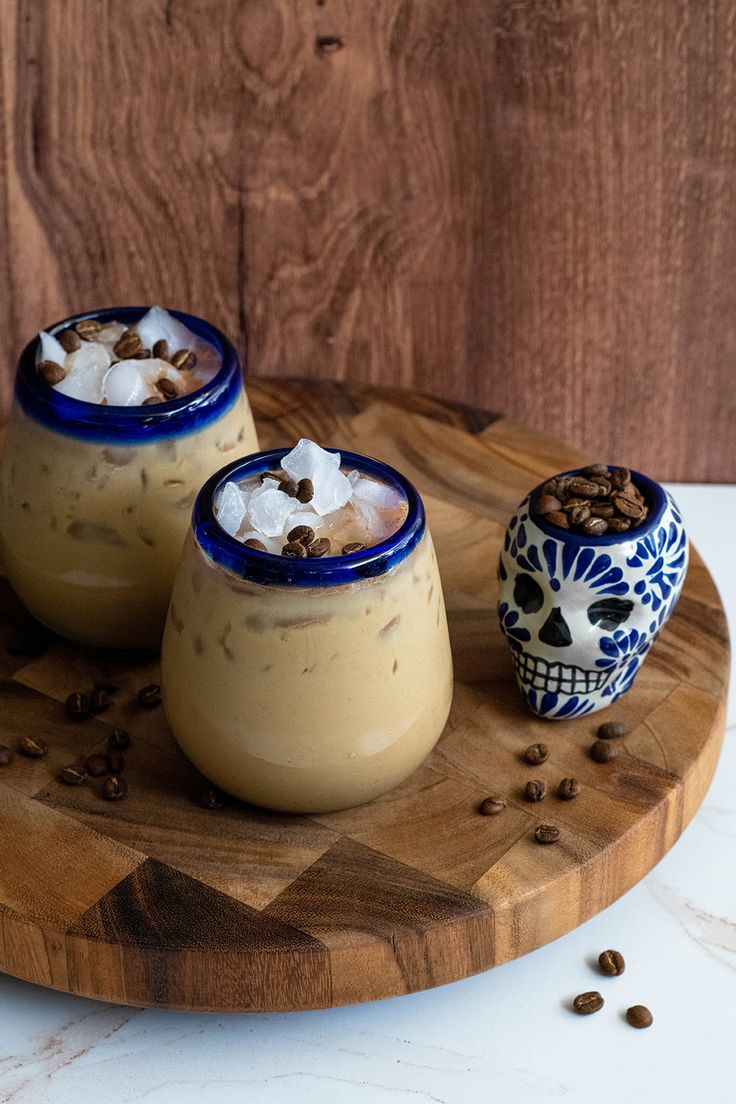 three desserts are sitting on a wooden board with sugar and coffee beans around them