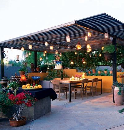 an image of a patio with lights hanging from the roof and plants in pots on the ground