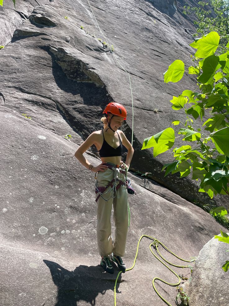 a woman standing on top of a rock while holding onto a rope and wearing a helmet