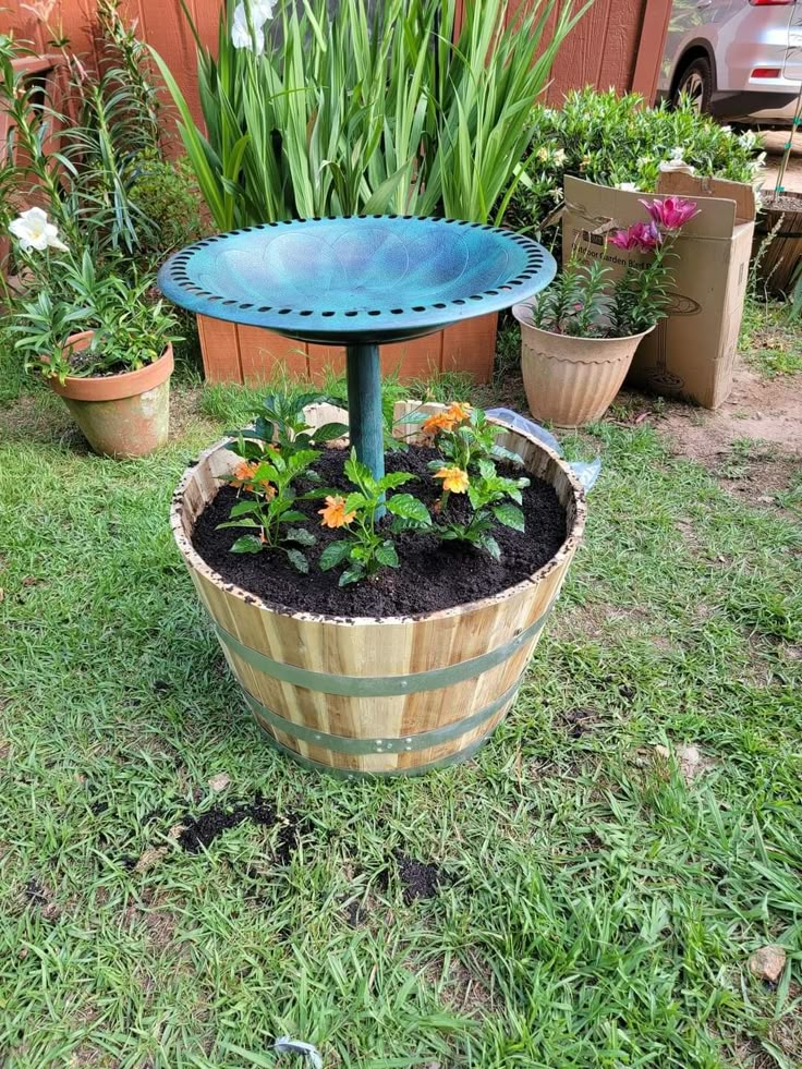 a potted planter sitting on top of a grass covered field next to a wooden barrel