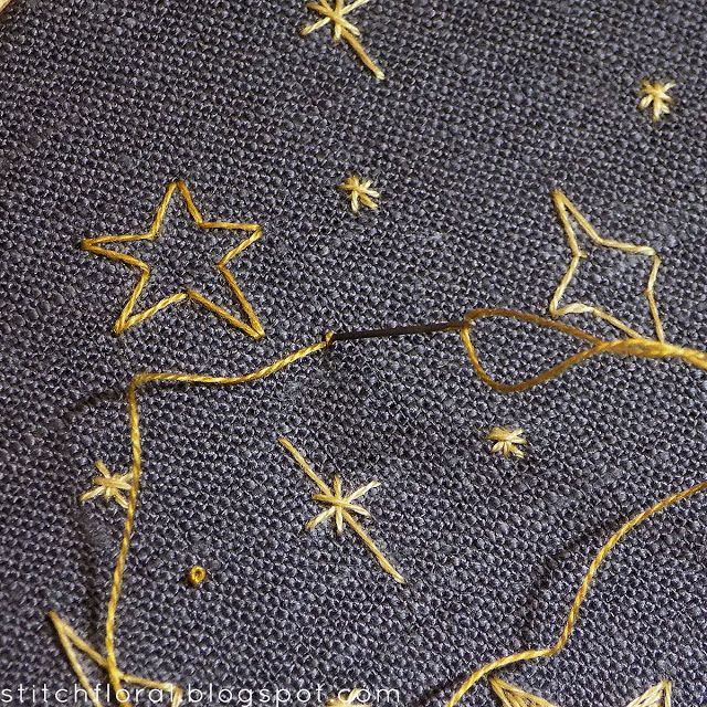 some gold stars on a blue fabric with yellow thread and sequins in the middle