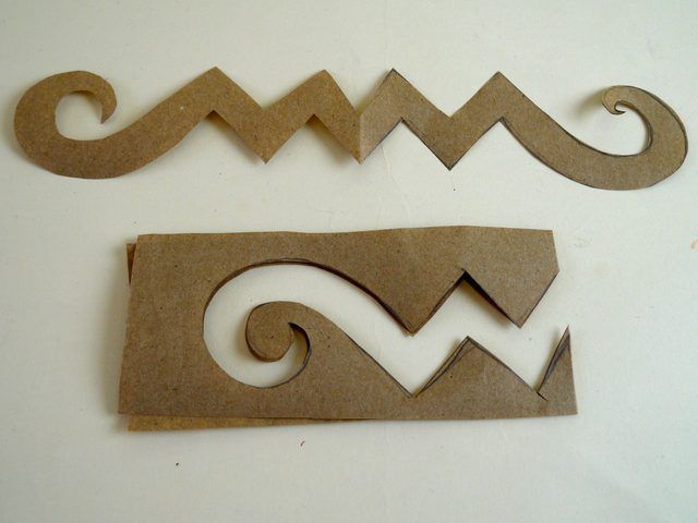 two pieces of cardboard cut out into the shape of letters with swirls on them