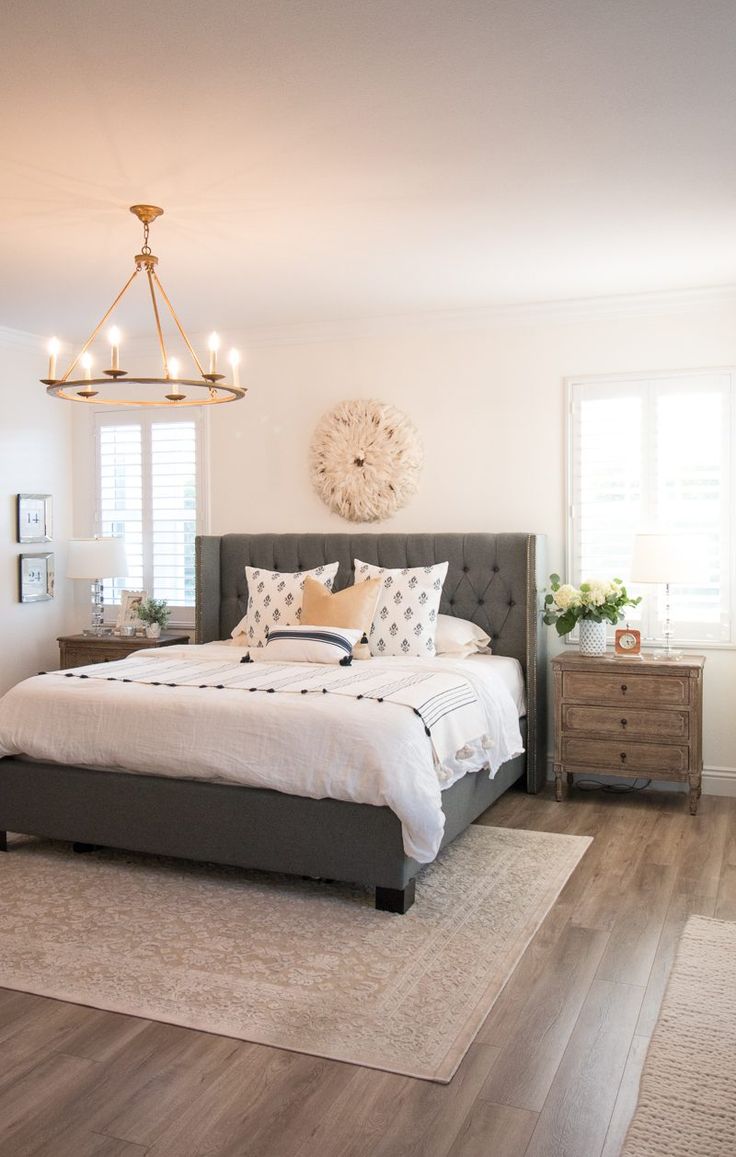 a bedroom with a bed, dresser and chandelier