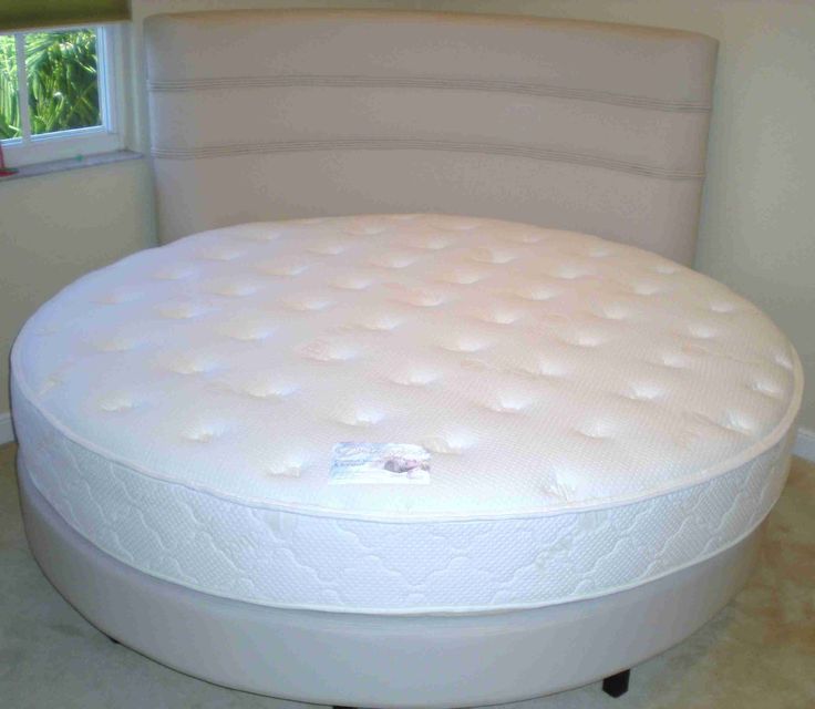 a white round bed sitting on top of a tiled floor next to a window in a room