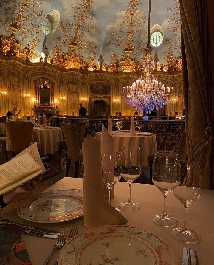 a fancy dining room with chandelier and table settings