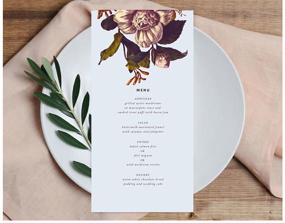 a white plate topped with a menu next to a green leafy plant on top of a wooden table