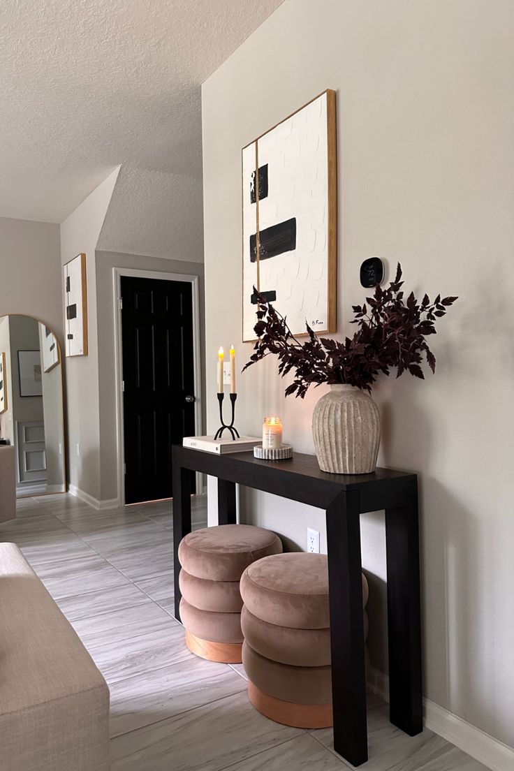 a living room with two stools and a vase on the table in front of it