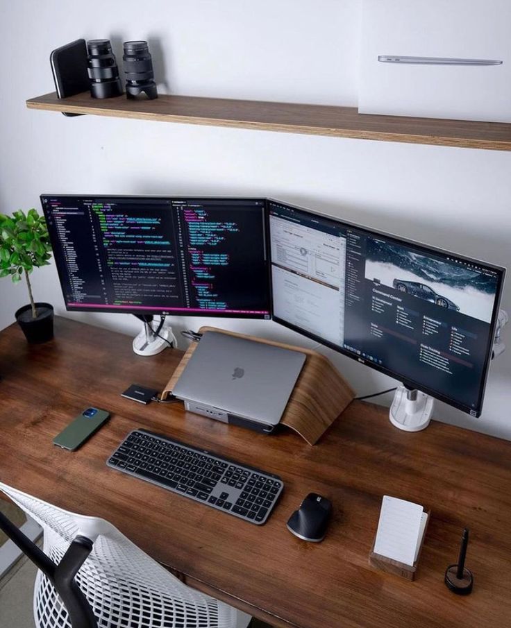 two computer monitors sitting on top of a wooden desk