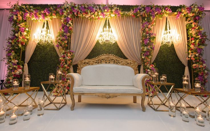 a white couch sitting under a window next to a table with candles and flowers on it