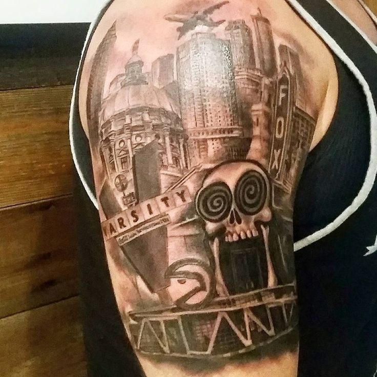 a man's arm with a skull and cityscape tattoo design on it