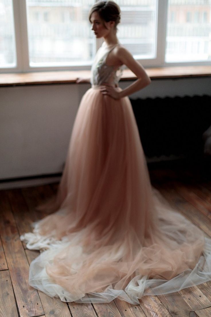 a woman standing in front of a window wearing a dress with sheer tulle on it