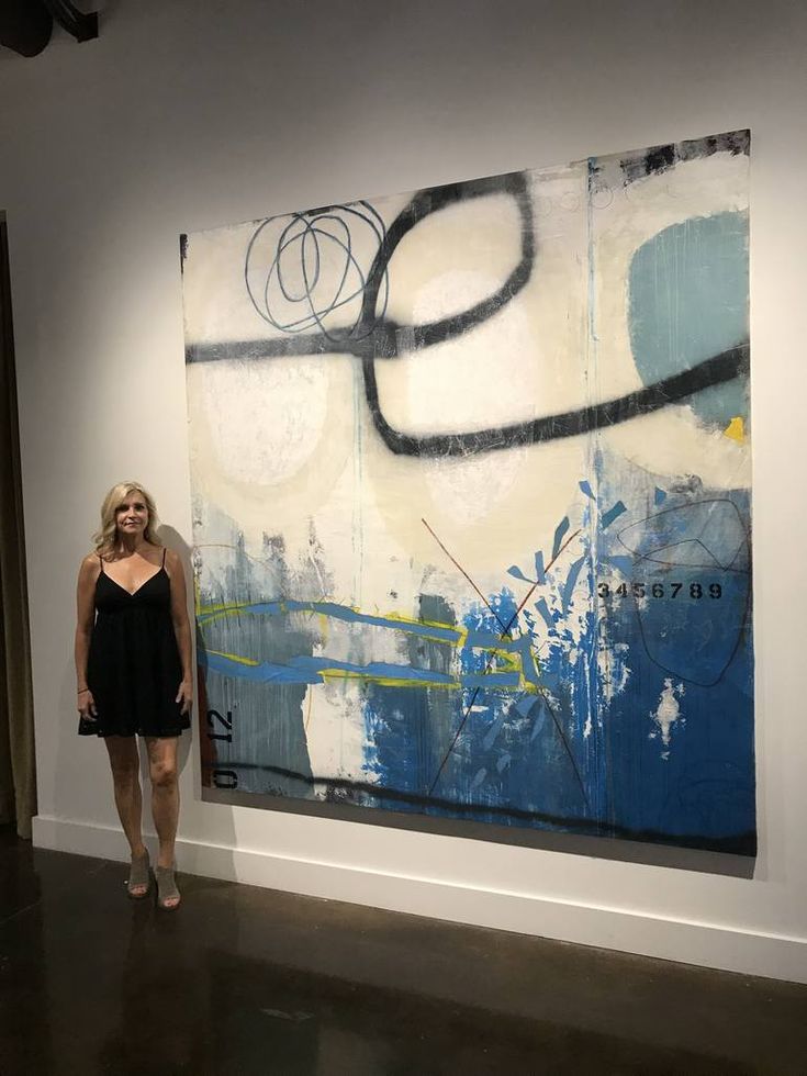 a woman standing in front of a large painting