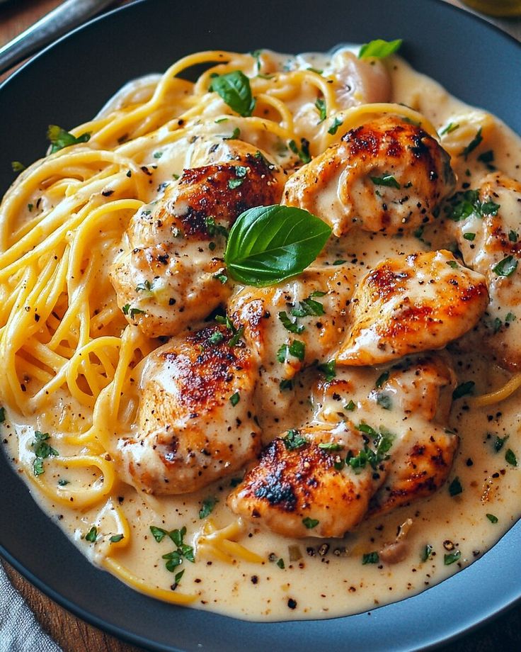 a plate of pasta with chicken and sauce on it, garnished with parsley