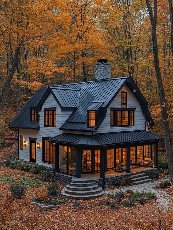 a house in the woods surrounded by trees with autumn leaves on the ground and foliage around it