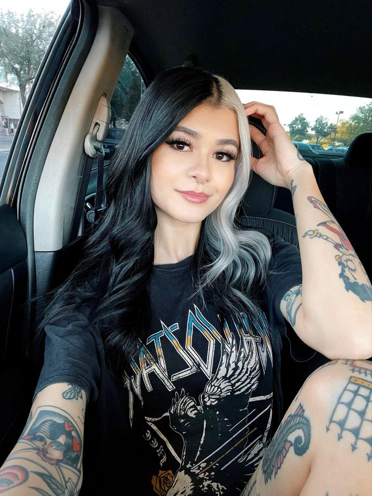 a woman sitting in the back seat of a car with tattoos on her arms and shoulder