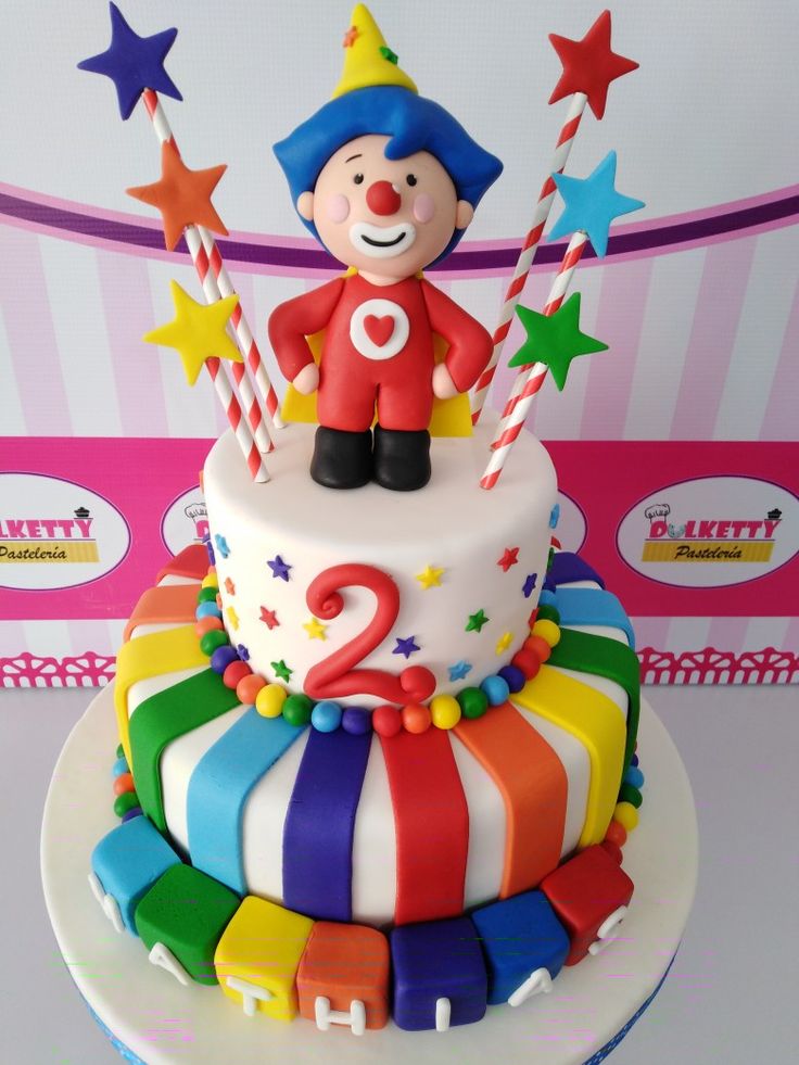 a colorful birthday cake with a clown figure on top