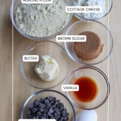 Ingredients for cottage cheese chocolate chip cookies in clear glass bowls on a wooden table.