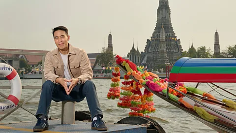 Thai actor Dom Hetrakul sitting in front of the Wat Arun temple and a water boat (Credit: Phollachej Rattanwacherin)