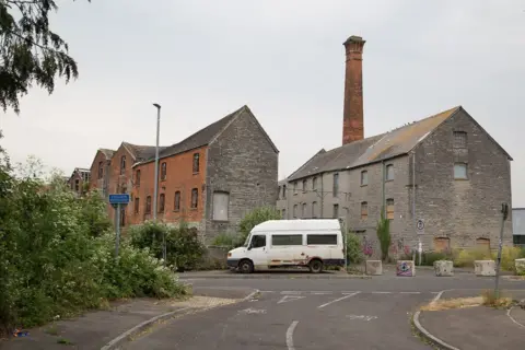 Jason Shrubb An old white transit van outside brick buidlings