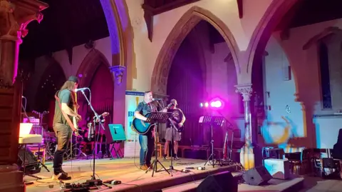 Blues in the Pews A blues band playing on stage in the nave of St John's church