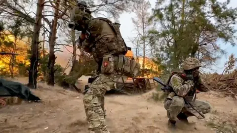 EPA Russian soldiers cover their ears as a Giatsint-B field gun is fired towards Ukrainian positions somewhere in Russia, taken 19 September