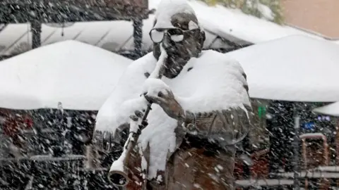 A statue of a jazz musician playing a horn is covered in snow in new orleans.