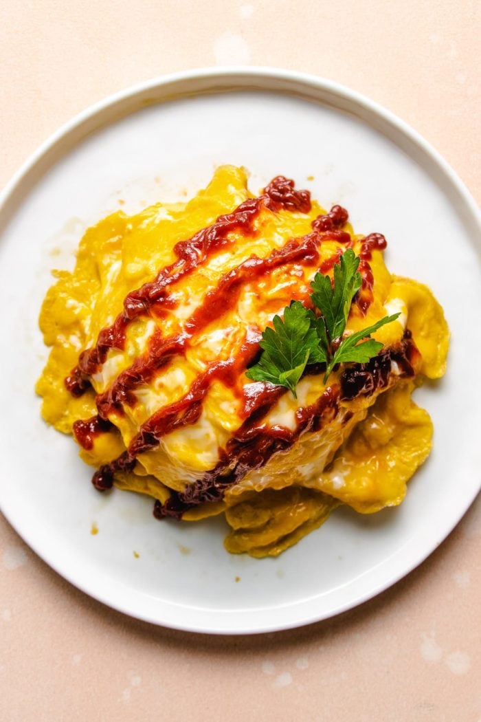 Photo shows finished shot of Japanese rice omelette with ketchup on top over a white plate