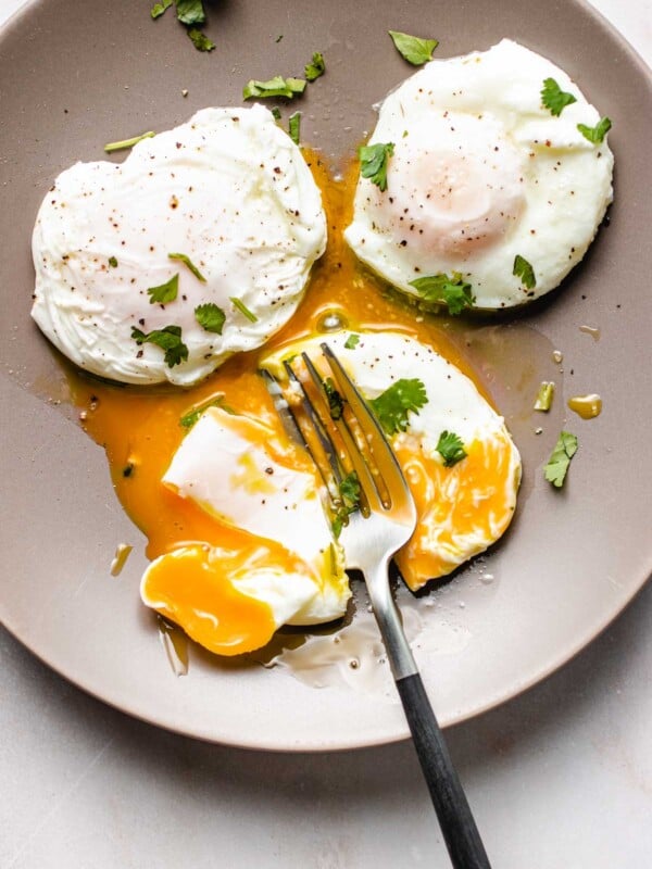 Photo shows 3 perfectly poached eggs made in an air fryer and served on a light gray color plate