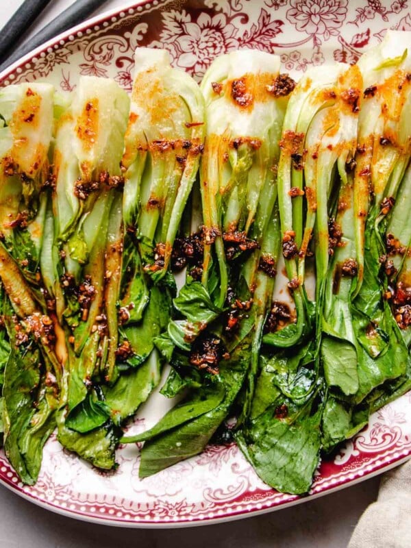 An overhead shot shows a big plate of roasted bok choy served on a platter with garlic chili sauce