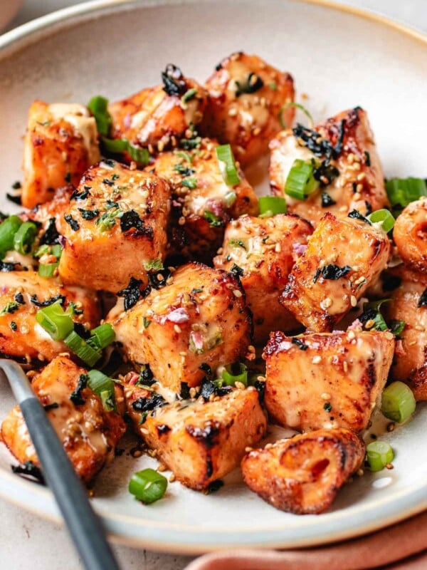 Salmon chunks sliced and seasoned then either air fried or oven baked and coated with bang bang sauce on a plate.