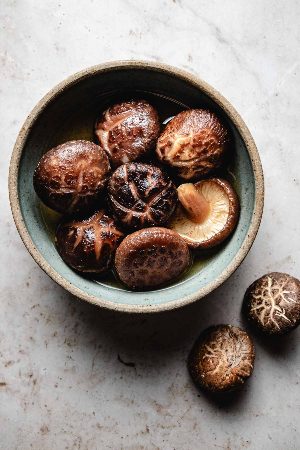 Photo shows a bowl of rehydrated dried shiitake mushrooms soaking in the liquid.