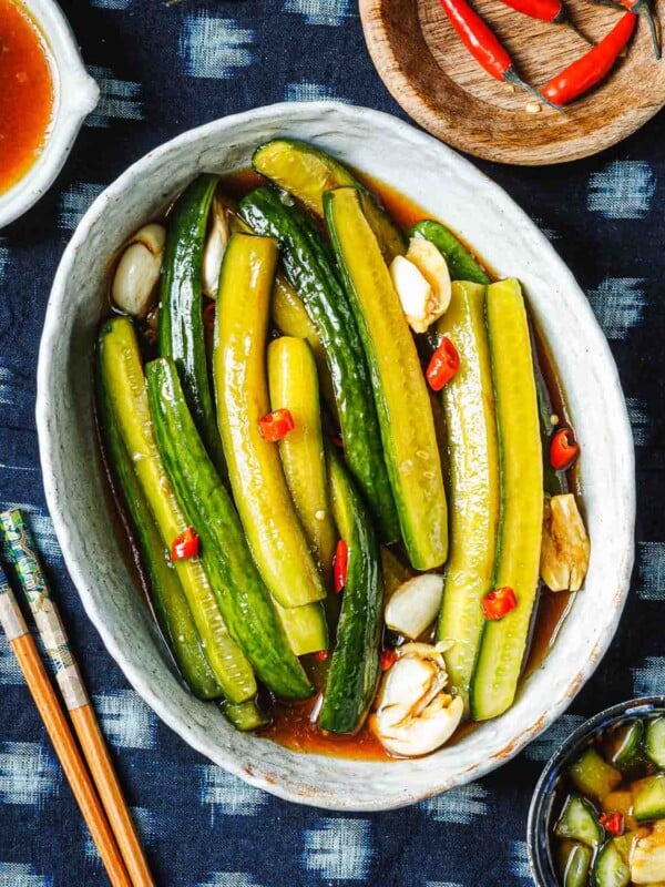 Feature image shows Persian cucumbers sliced to spears and marinated with Asian pickling juice and served in a white oval plate.