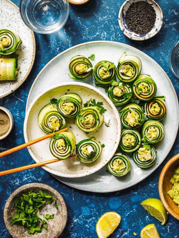 Feature image shows cucumber roll ups with avocado and turkey deli meat, served on a white plate with chopsticks.