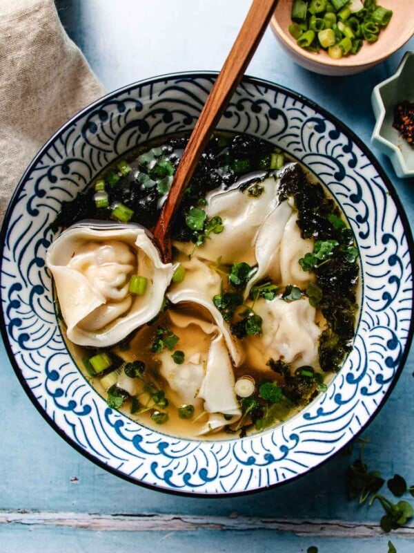 Feature image shows a bowl of shrimp wonton soup with northern Chinese style wonton broth served in a blue white color bowl.