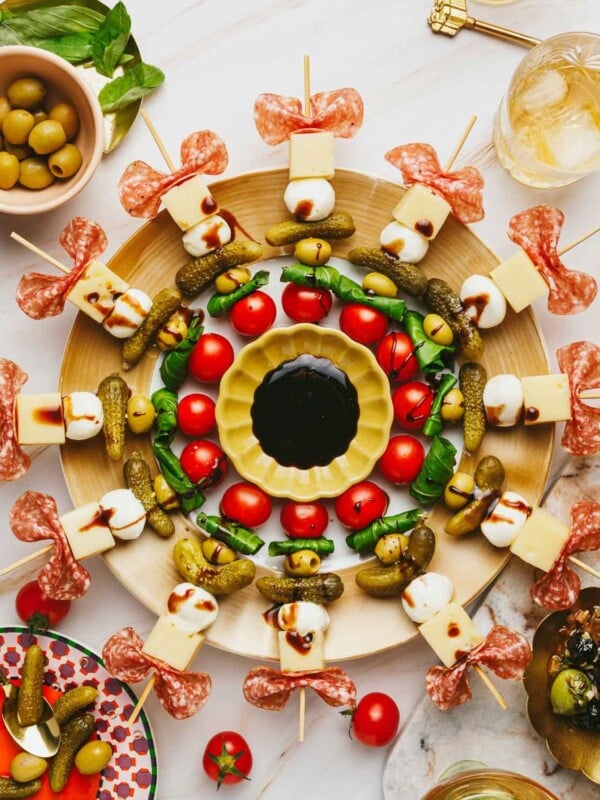 Feature image shows charcuterie skewers served over a large charcuterie board with garnishes on the side.