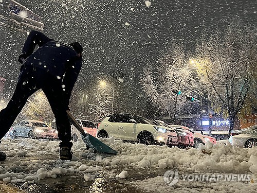 A person removes snow off a road near Gyeongbok Palace in Seoul on Nov. 27, 2024, after parts of the city received more than 15 centimeters of snow overnight. (Yonhap)