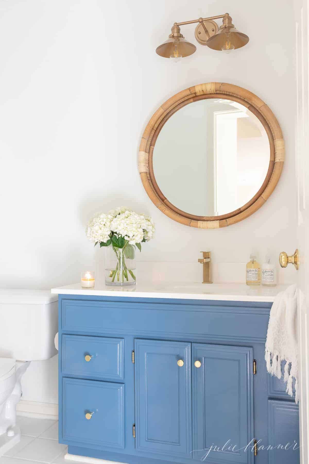 A blue and white bathroom with brass bathroom light fixtures.