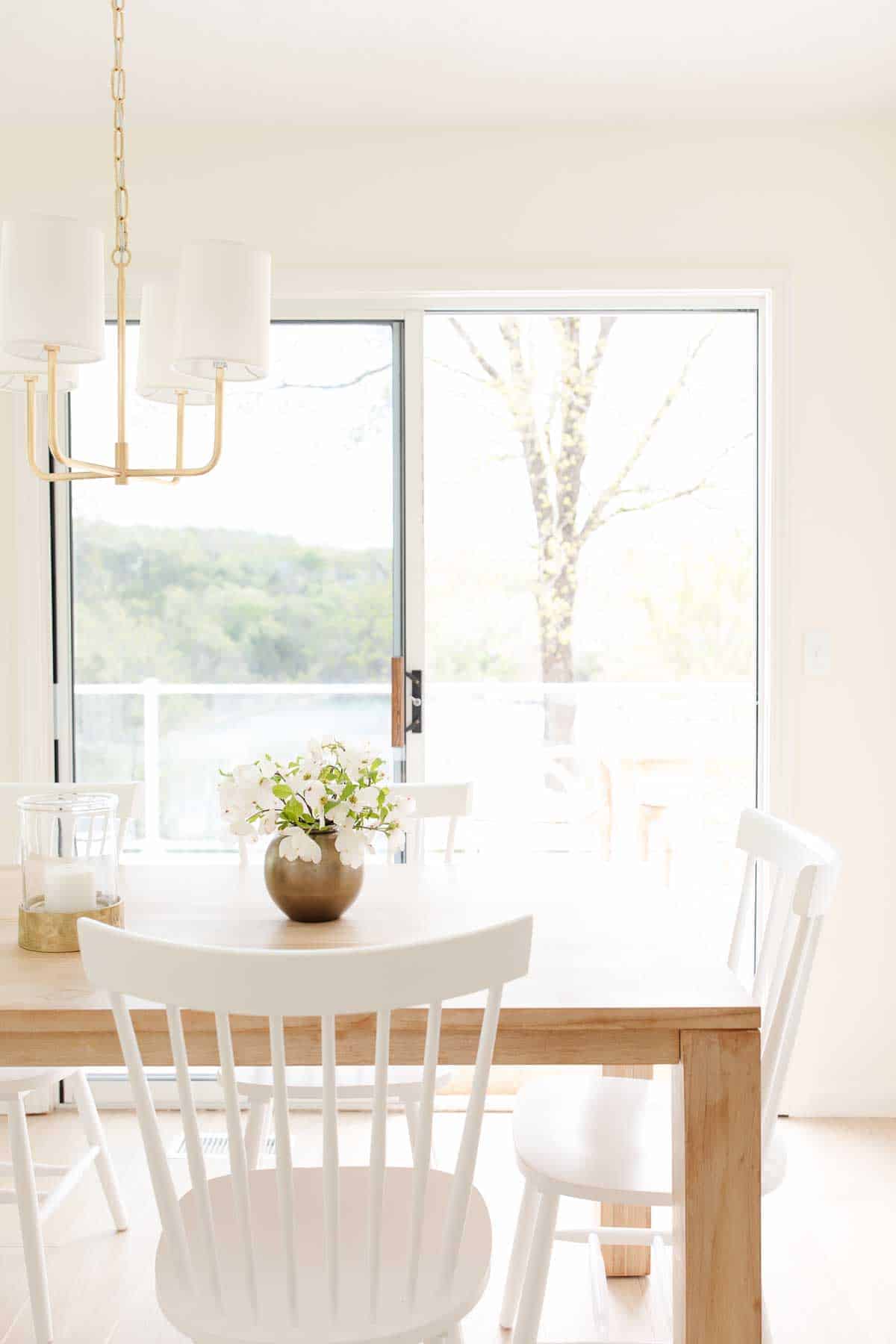 modern brass chandelier with shades over a kitchen table with flowers