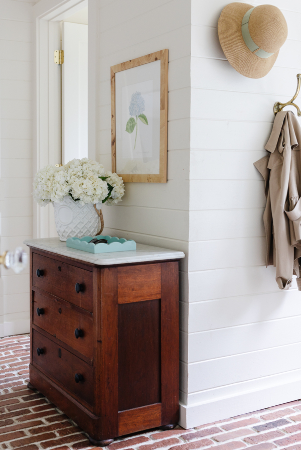 A mudroom with an antique chest and hydrangeas in a vase